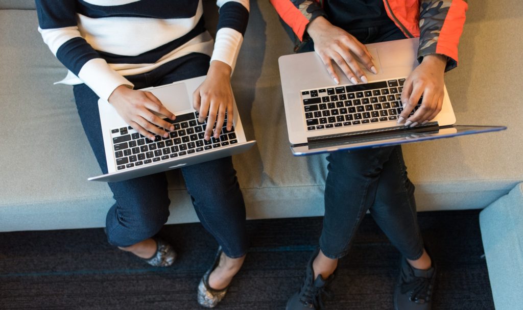 Two women sitting at laptops typing
